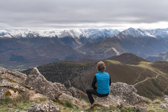 Mountaineer sitting on a mountaintop contemplating the snow-capped peaks