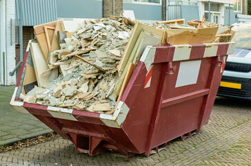 a waste bin filled with construction rubble sits outside in a parking lot
