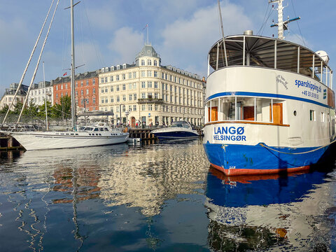 Copenhagen, Denmark - September 02, 2025: Tourist boat Lango docked in harbor reflecting historic buildings under morning sunlight