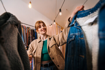 Fototapeta premium A Fashionable Young Woman Enthusiastically Shopping for Vintage Clothes in a Trendy Store