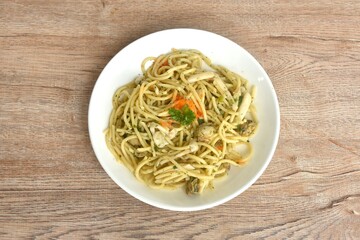 spicy stir fried spaghetti with scallop in garlic butter sauce topping shrimp egg on plate 