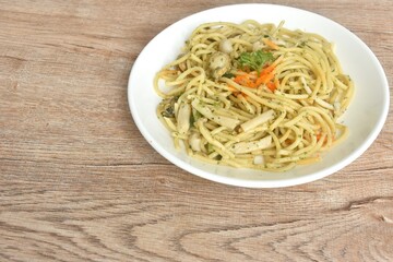 spicy stir fried spaghetti with scallop in garlic butter sauce topping shrimp egg on plate 