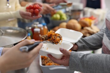 Volunteers giving food to homeless people in shelter, closeup