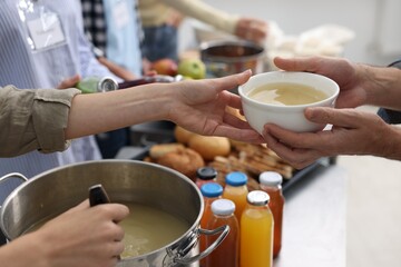 Volunteers giving food to homeless people in shelter, closeup