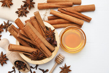 Different spices (anise, cinnamon, cloves) and honey for mulled wine on white table, flat lay