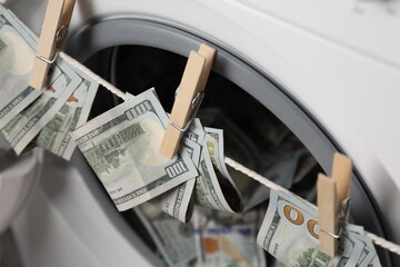 Banknotes hanging on clothesline near washing machine, closeup