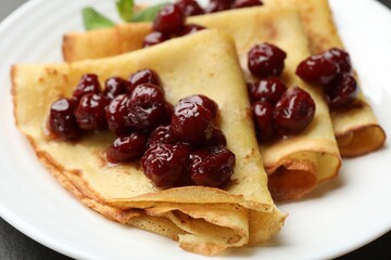 Tasty crepes with cherries and mint on table, closeup
