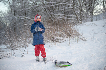 Charming girl with a sled on a snowy winter slope