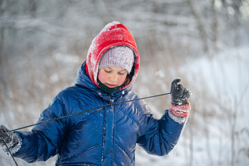 Portrait of a charming girl holding a sled rope in snowy winter