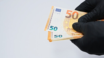 Close-up of hands in black gloves counting euro banknotes, symbolizing crime, corruption, money laundering, illegal finance, and underworld economic activities.