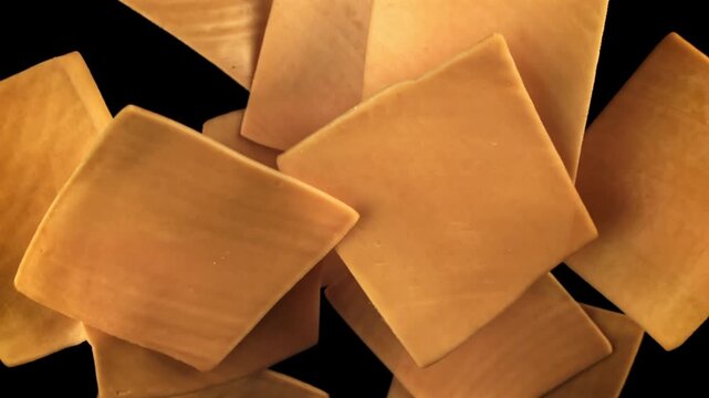 Sliced cheddar cheese flies on a black background. Filmed on a high-speed camera at 1000 fps. High quality FullHD footage