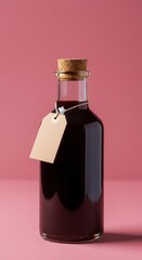 Glass bottle with dark liquid and blank tag against pink background