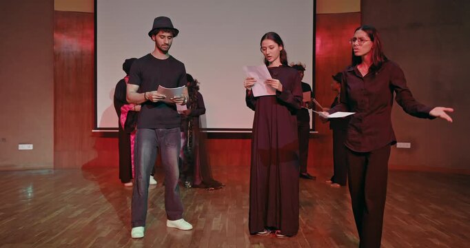 Indian young adult gen z male female hold script paper do acting scene practice indoor hall stage room Teen girl boy group team talk speak read new story line learn next day drama play at studio place