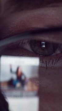 Close view of eyes behind eyeglasses showing images on screens in daily life