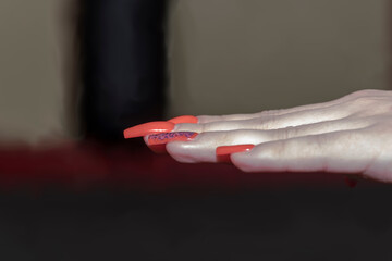 Fantazyjnie pomalowane, długie paznokcie u dłoni kobiety wykonującej uderzenie Schihon Nukite Tsuki. Palce są wyciągnięte, a paznokcie wyraźnie widoczne, odbijając światło. 