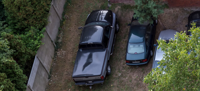 Polska, Ostrowiec Świętokrzyski, 10 września 2025, 17:15. DODGE RAM 1500 przed ceglanym murem na trawie. Amerykański terenowy pikap 4x4, stoi obok dw&oacute;ch samochod&oacute;w osobowych. 