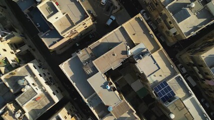 Bird’s eye top down view of dense Maltese rooftops, narrow streets, and historic stone urban patterns, textured backdrop with cars driving