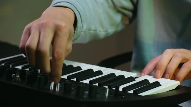 Close up of a creative musician playing and composing music on a digital synthesizer. Music producer creating an electronic track using a modern midi keyboard and adjusting the sound settings