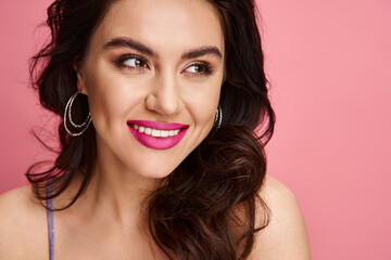 Obraz premium Radiant young woman smiles brightly against a vibrant pink backdrop in a cheerful moment