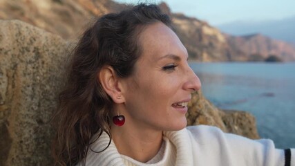 Woman cliff sea, close-up of a happy woman enjoying the stunning rocky coastal view and sunset over the calm ocean water.