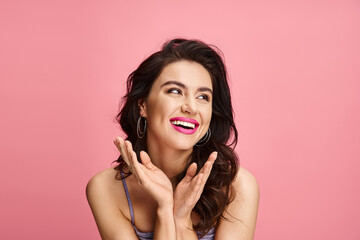 Joyful young woman with radiant smile enjoying playful moment against pink backdrop