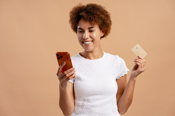 Smiling woman making an online payment via mobile phone, holding a credit card