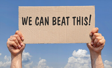 Hands holding a piece of cardboard with the inscription "We can beat this"
