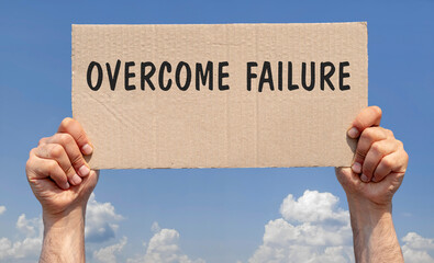 Hands holding a piece of cardboard with the inscription "Overcome failure"