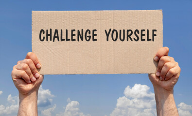 Hands holding a piece of cardboard with the inscription "Challenge yourself"