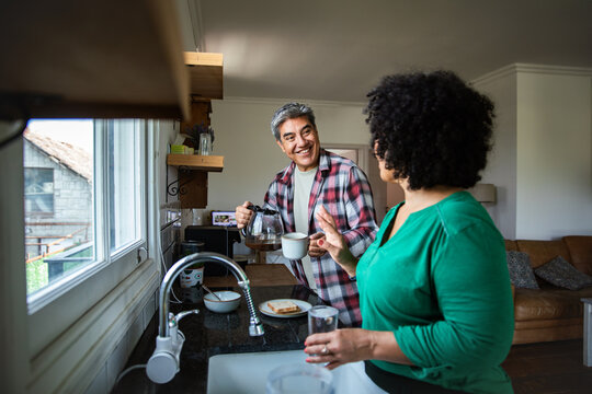 Mature couple smiling while making morning coffee in home kitchen - Powered by Adobe