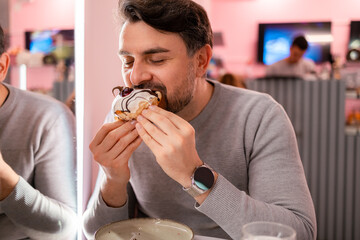 Man enjoying a delicious donut at a vibrant dessert cafe during a casual outing