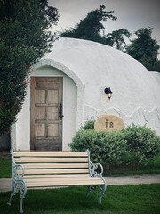 Ratchaburi, Thailand :Beautiful architecture of white dome bungalow with arch window and door linked by a walkway on lush green lawn with mountain view at IGLOO Suanphueng resort.