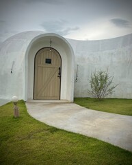 Ratchaburi, Thailand :Beautiful architecture of white dome bungalow with arch window and door linked by a walkway on lush green lawn with mountain view at IGLOO Suanphueng resort.