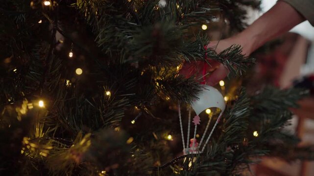Woman hanging The Fairy tale Parachute Christmas tree decoration on green branch in living room, preparing home for Happy Christmas celebration. Winter holidays routine 4K video.