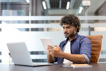 Muslim young man is working in the office with a laptop and using a tablet