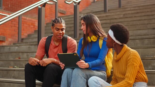 Diverse university students collaborating on project using a digital tablet