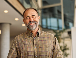 Portrait of a smart inteligent senior businessman holding a laptop computer in office