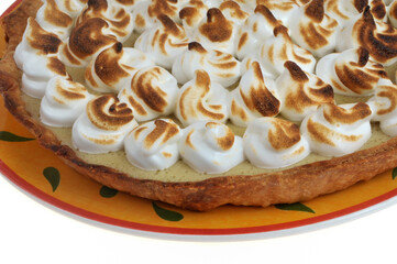 Vue partielle d'une tarte au citron meringuée dans un plat en gros plan sur fond blanc