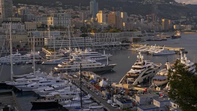 A stunning sunset panorama showing a packed luxury marina with mega-yachts, sailboats, and motorboats set against an impressive coastal skyline in 4K Monaco 7 May 2019
