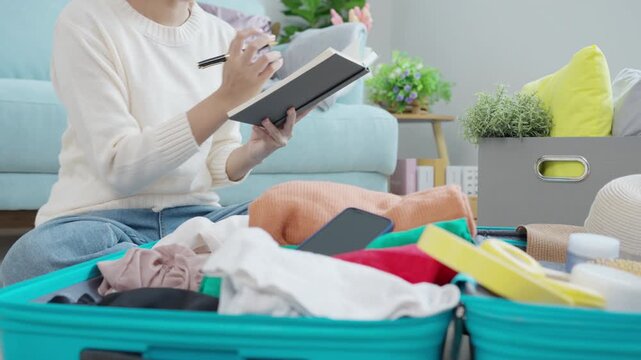 Travel bag. female are checking the detail and quantity of items used during the trip by checklist. Young women are prepare clothes and personal belongings. Pack your luggage before travel.