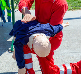 First aid instructor performing back blows on child dummy