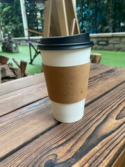 Rustic wooden table with takeaway coffee cup in outdoor cafe