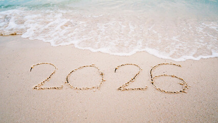 number 2026  write on sandy beach for new year, with ripple sea wave crashing with white bubble, 2026 New Year celebration concept