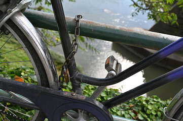 Bicycle secured to railing along a peaceful riverbank with reflections on the water in the background