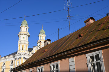 HTall towers of a historic cathedral rise above a nearby roof on a sunny day