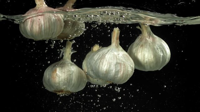 The heads of fresh garlic fall under the water. Filmed on a high-speed camera at 1000 fps. High quality FullHD footage