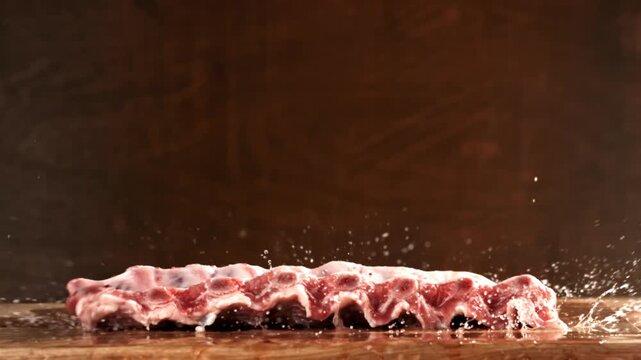 Raw pork ribs fall onto a cutting board. Filmed on a high-speed camera at 1000 fps. High quality FullHD footage