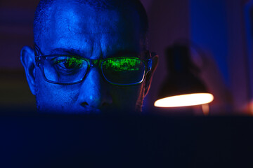 Man focusing on digital stock market charts reflecting in his glasses