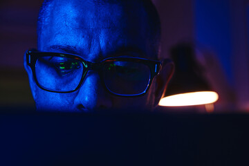 Person wearing glasses with market data reflection, actively engaging in online finance