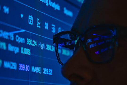 Trader's eye viewing stock market statistics and financial data reflecting in glasses - Powered by Adobe
